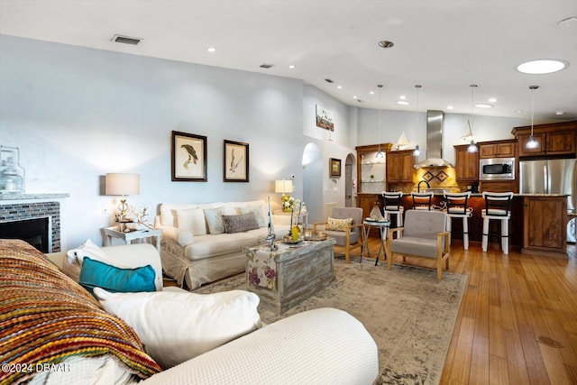 living room with a fireplace, a high ceiling, and light wood-type flooring