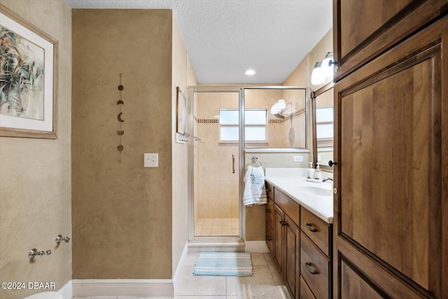 bathroom with vanity, an enclosed shower, a textured ceiling, and tile patterned floors