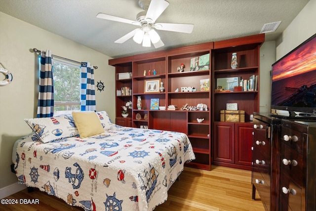 bedroom featuring ceiling fan, a textured ceiling, and light wood-type flooring