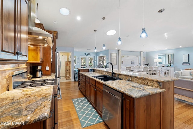 kitchen featuring light hardwood / wood-style floors, sink, appliances with stainless steel finishes, hanging light fixtures, and a large island