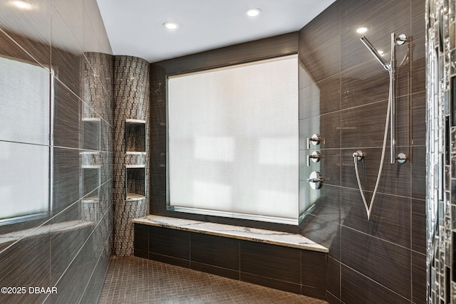 bathroom featuring a tile shower, tile patterned flooring, and tile walls