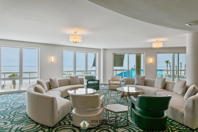 living room featuring carpet, plenty of natural light, and a water view