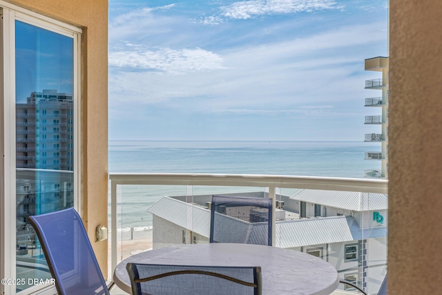 balcony with a water view and a view of the beach