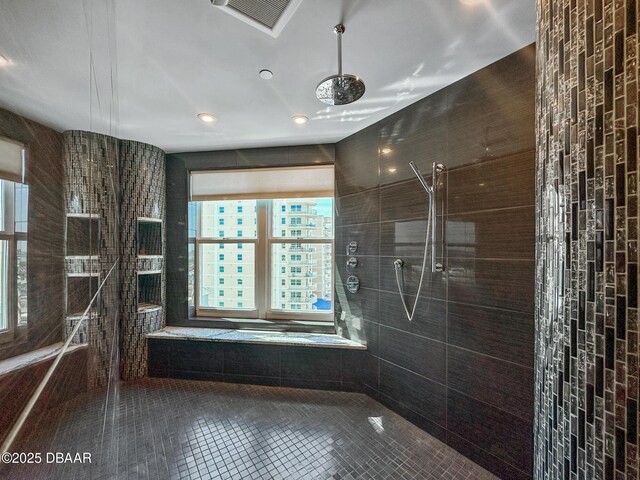 bathroom featuring tile patterned flooring, a tile shower, and tile walls