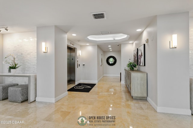 hallway featuring elevator and a tray ceiling