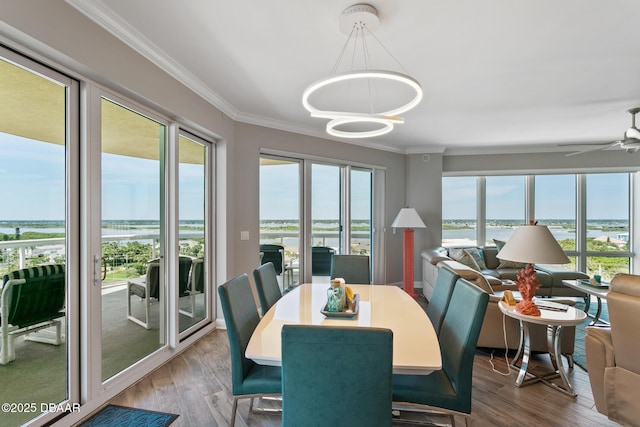 dining room with ceiling fan with notable chandelier, a water view, wood-type flooring, and crown molding