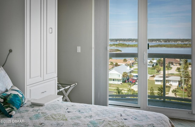 bedroom featuring a water view and multiple windows