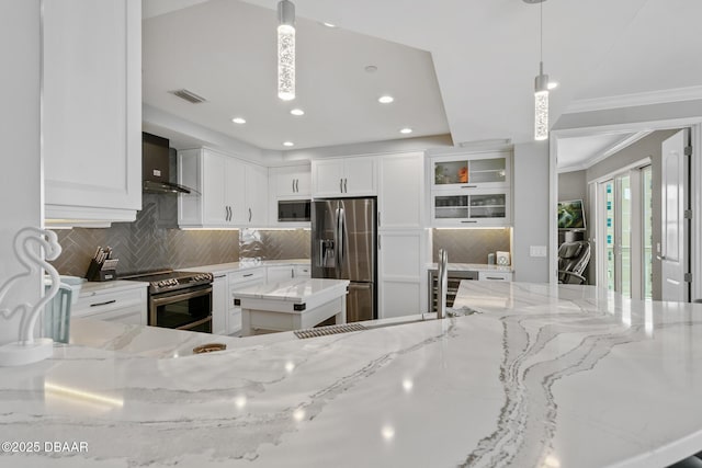 kitchen with light stone countertops, hanging light fixtures, tasteful backsplash, white cabinets, and appliances with stainless steel finishes