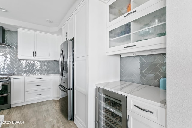 kitchen with light stone countertops, appliances with stainless steel finishes, white cabinetry, and beverage cooler