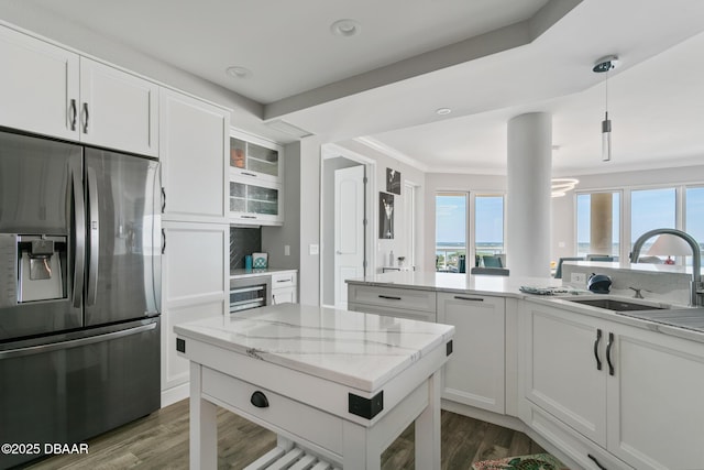 kitchen with light stone counters, sink, white cabinets, stainless steel fridge with ice dispenser, and hanging light fixtures