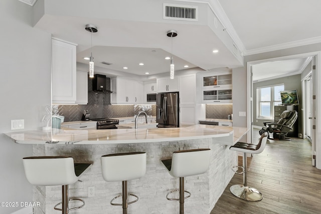 kitchen with white cabinetry, hanging light fixtures, kitchen peninsula, a breakfast bar, and appliances with stainless steel finishes