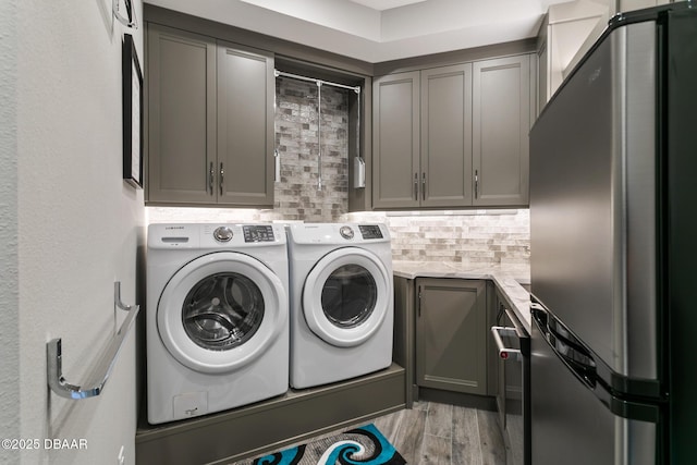 washroom featuring washing machine and dryer, cabinets, and light hardwood / wood-style floors