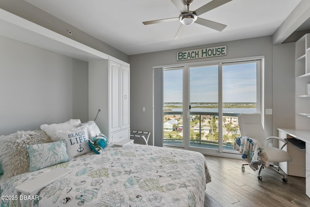 bedroom with hardwood / wood-style floors, ceiling fan, a water view, and a closet