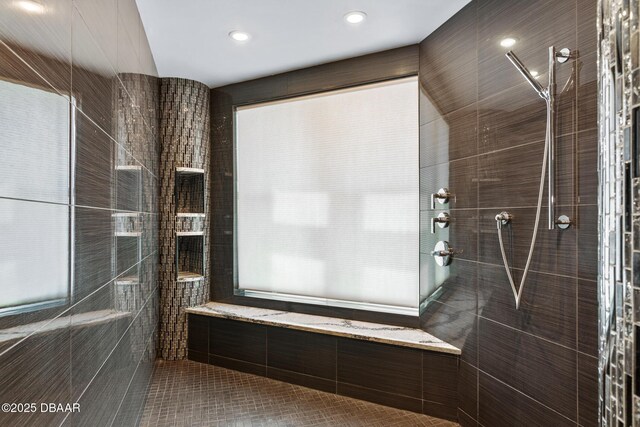 bathroom with tile patterned flooring, tiled shower, and tile walls