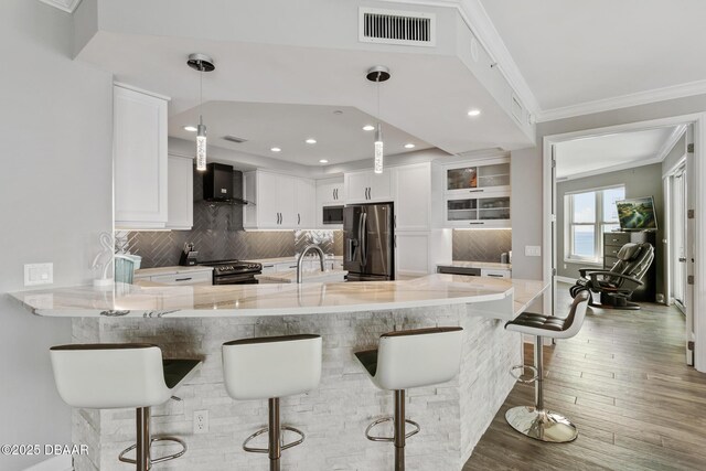 kitchen with hanging light fixtures, stainless steel appliances, kitchen peninsula, a breakfast bar area, and white cabinets