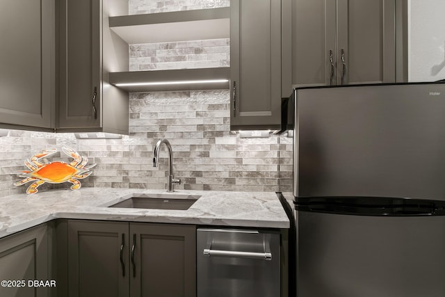 kitchen with backsplash, sink, gray cabinets, stainless steel fridge, and light stone countertops