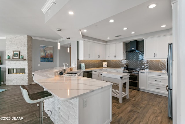 kitchen with decorative backsplash, stainless steel appliances, white cabinetry, and wall chimney range hood