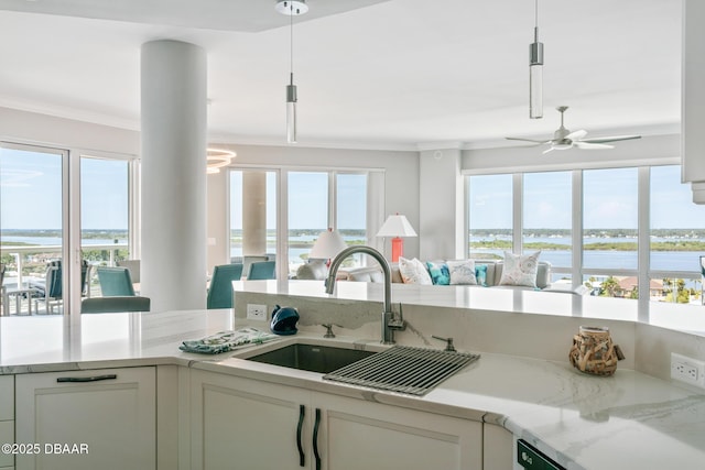 kitchen with white cabinetry, sink, a water view, and hanging light fixtures