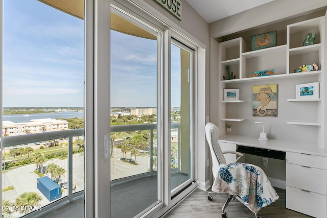 home office with hardwood / wood-style floors, a water view, and built in features