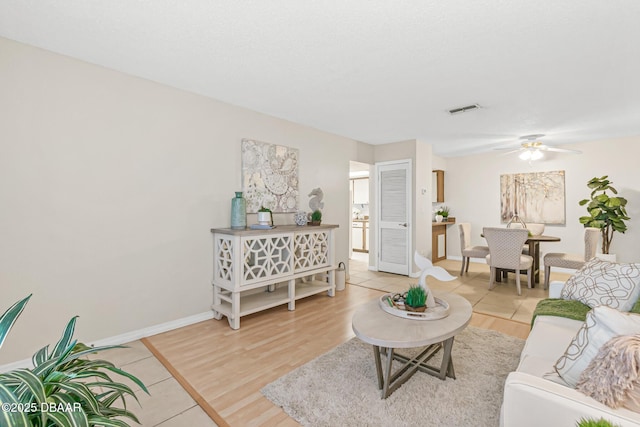 living room with visible vents, a ceiling fan, light wood finished floors, and baseboards
