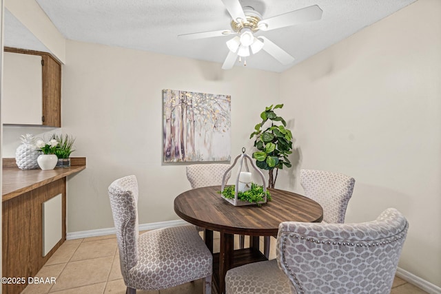 dining room featuring baseboards, a ceiling fan, a textured ceiling, and light tile patterned flooring