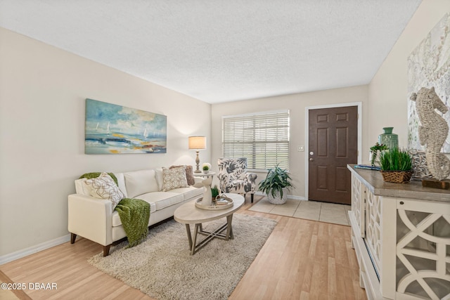living area featuring a textured ceiling, light wood-type flooring, and baseboards