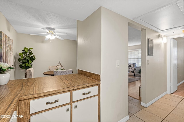 kitchen featuring light tile patterned flooring, ceiling fan, white cabinetry, and a textured ceiling