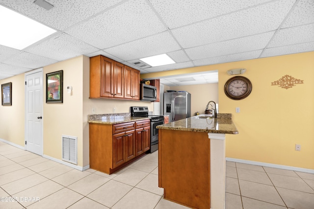 kitchen featuring a drop ceiling, stainless steel appliances, and dark stone counters