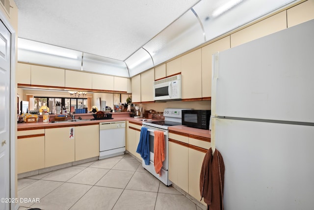 kitchen featuring sink, cream cabinets, white appliances, and light tile patterned flooring