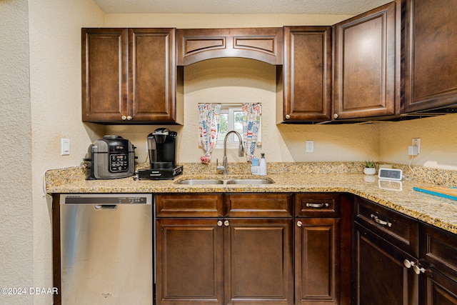 kitchen featuring dark brown cabinetry, a textured ceiling, sink, stainless steel dishwasher, and light stone countertops