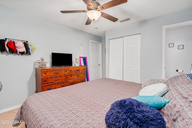 carpeted bedroom with a textured ceiling, ceiling fan, and a closet