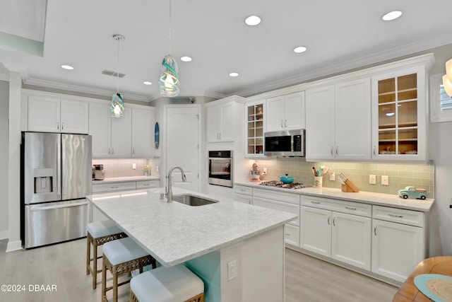 kitchen featuring sink, an island with sink, pendant lighting, appliances with stainless steel finishes, and white cabinetry