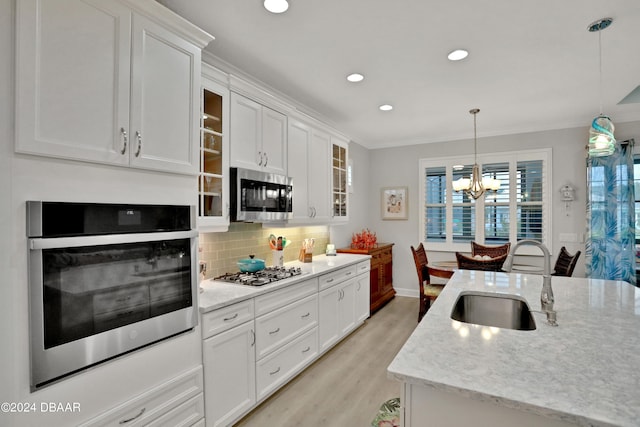 kitchen featuring white cabinetry, stainless steel appliances, hanging light fixtures, and sink