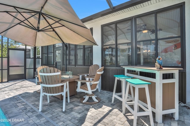 view of patio / terrace featuring a bar, a sunroom, and glass enclosure