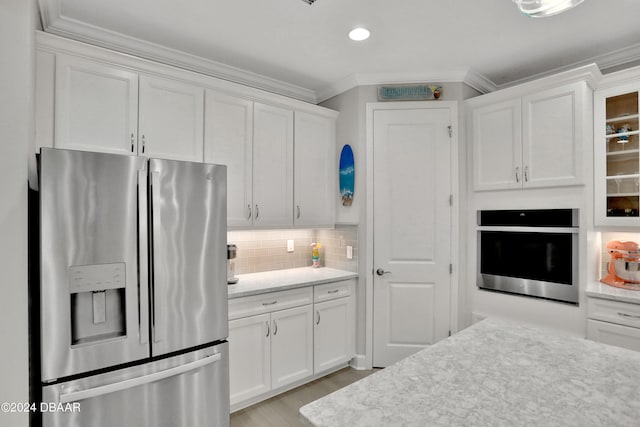 kitchen featuring stainless steel appliances, light stone countertops, white cabinetry, and backsplash