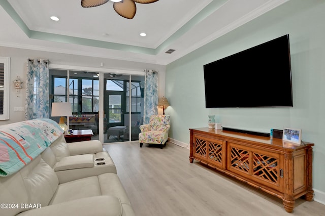 living room featuring light hardwood / wood-style floors, ceiling fan, crown molding, and a tray ceiling