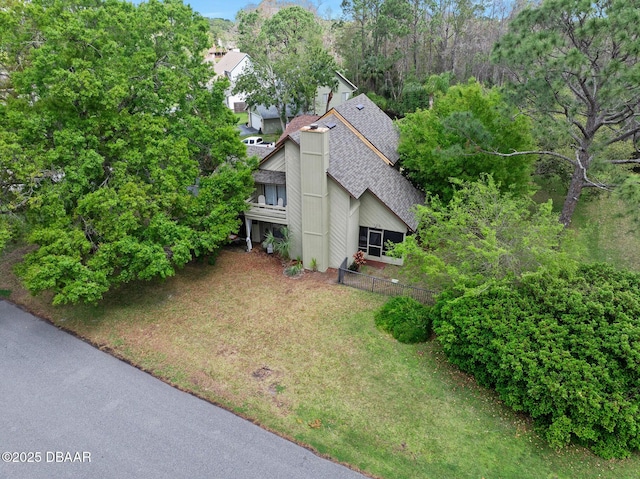 exterior space with roof with shingles and a lawn