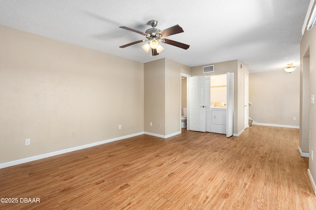 unfurnished room featuring washer / dryer, light hardwood / wood-style floors, and a textured ceiling