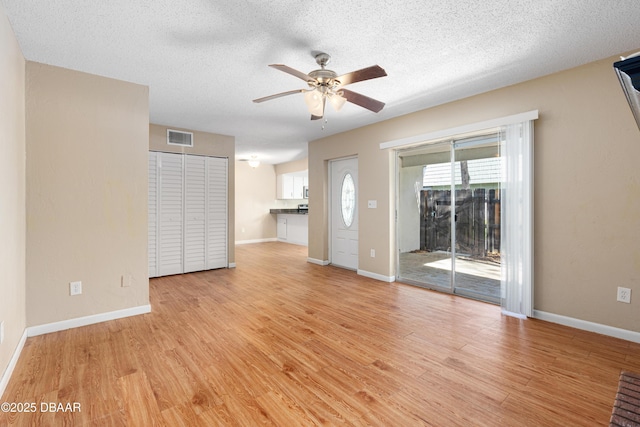 unfurnished living room featuring ceiling fan, light hardwood / wood-style flooring, and a textured ceiling