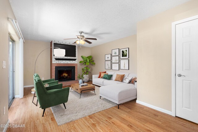 unfurnished living room with a brick fireplace, light hardwood / wood-style flooring, and a textured ceiling