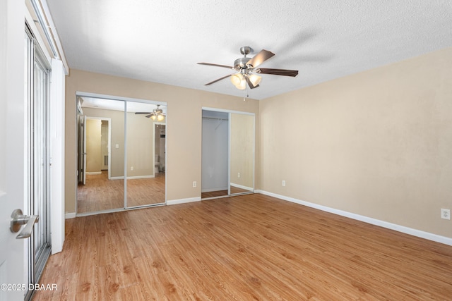 unfurnished bedroom with multiple closets, ceiling fan, a textured ceiling, and light hardwood / wood-style flooring