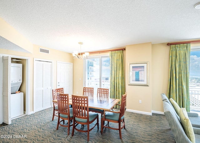 carpeted dining space featuring visible vents, baseboards, a chandelier, stacked washing maching and dryer, and a textured ceiling