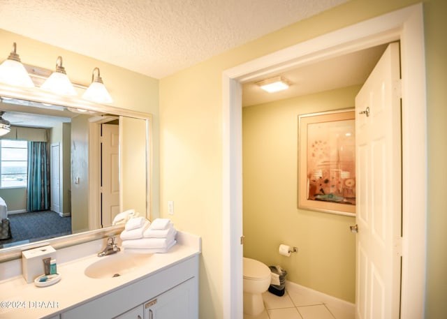 bathroom featuring vanity, baseboards, a textured ceiling, tile patterned floors, and toilet