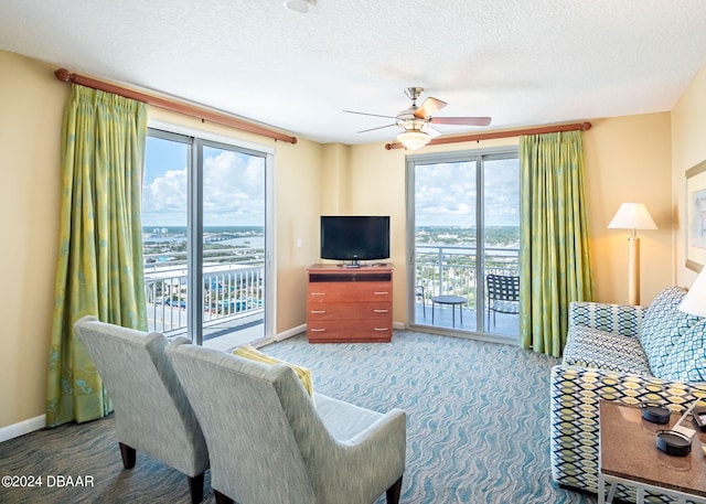 living room featuring a textured ceiling, carpet flooring, baseboards, and ceiling fan