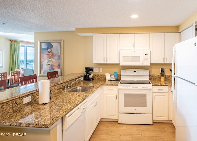 kitchen with white appliances, a peninsula, light wood-style flooring, a sink, and white cabinets