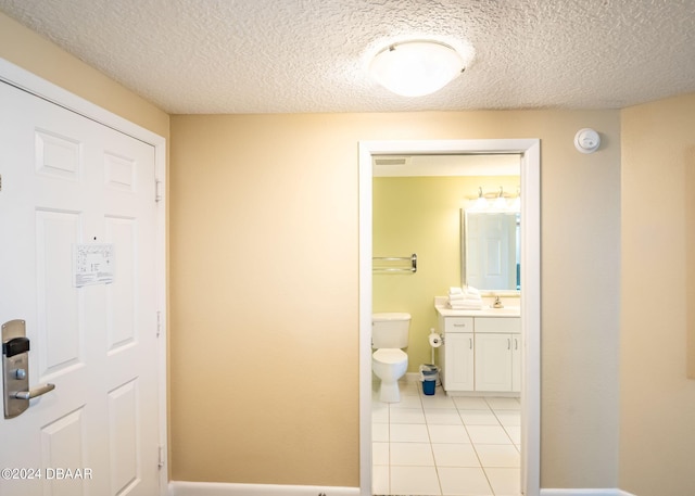 half bathroom featuring tile patterned flooring, visible vents, toilet, vanity, and a textured ceiling