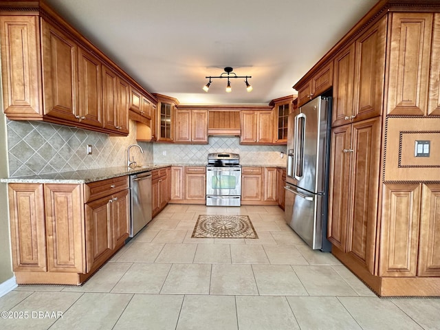 kitchen featuring tasteful backsplash, brown cabinetry, appliances with stainless steel finishes, light stone counters, and extractor fan