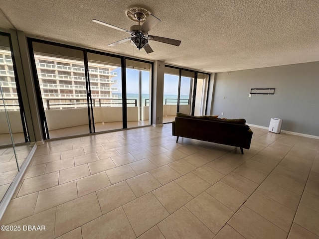 unfurnished living room featuring light tile patterned floors, ceiling fan, a textured ceiling, and baseboards