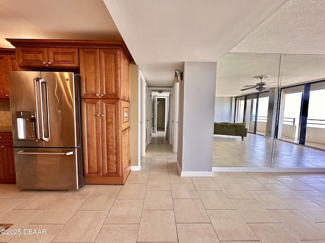 kitchen with stainless steel fridge, brown cabinetry, ceiling fan, a textured ceiling, and light tile patterned flooring