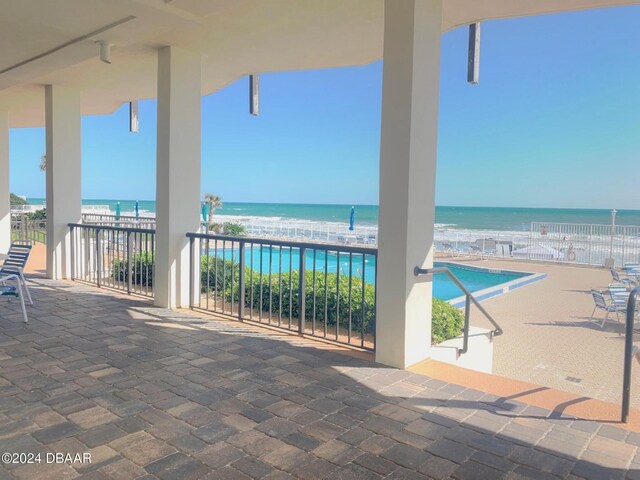 view of patio / terrace with a beach view, a water view, and a balcony